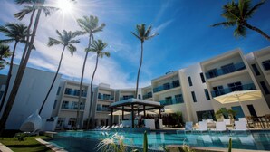 Un hôtel moderne doté d’une piscine, de palmiers et offrant une vue sur un ciel dégagé.