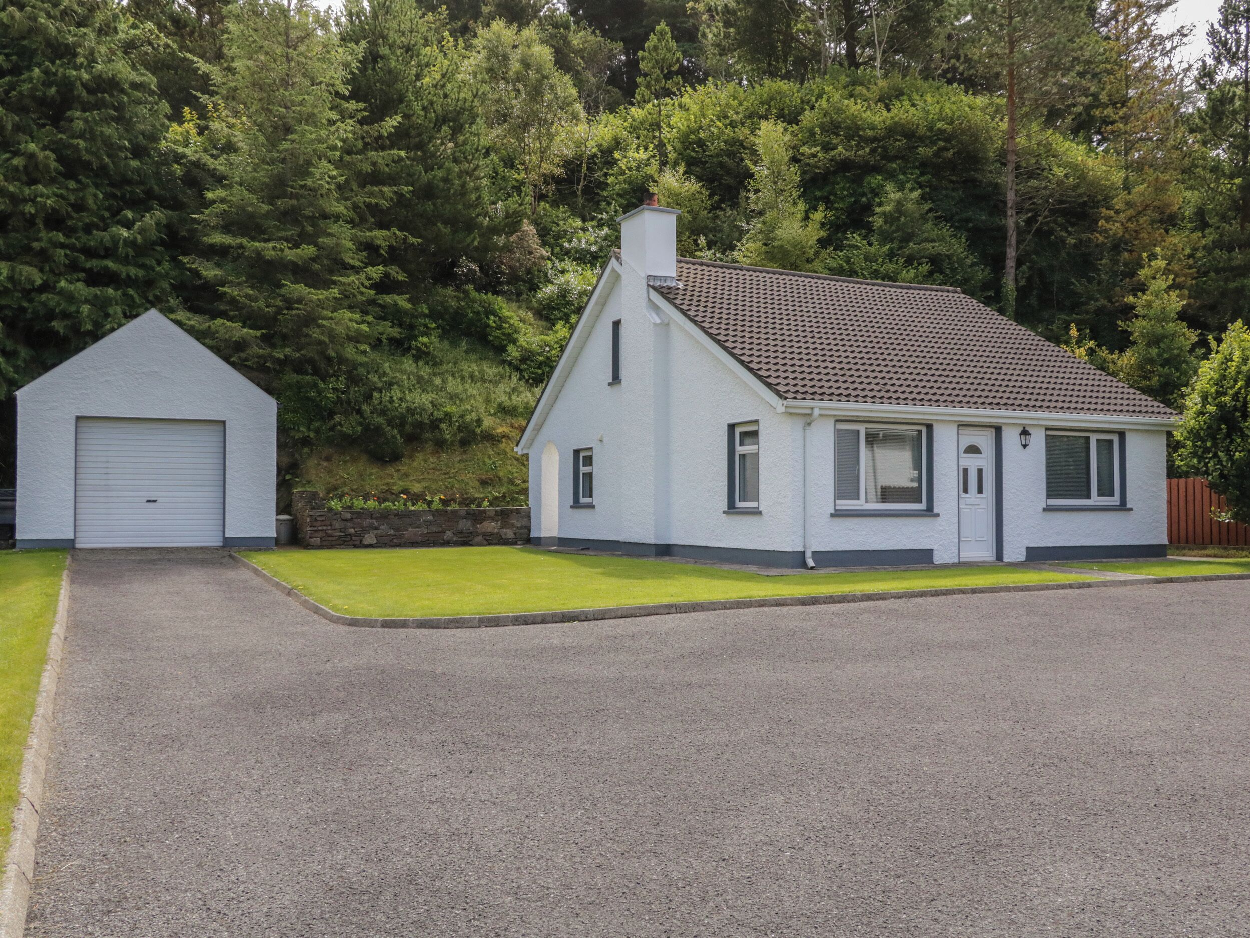 Ein zweistöckiges Haus mit Garage, einer kleinen Veranda und einem Ziegeldach.