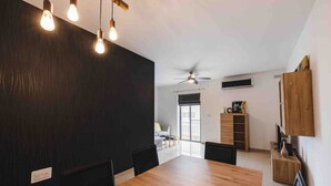 Ein moderner Essbereich mit Holztisch und -stühlen, einem Deckenventilator und einer Wand in Schwarz.