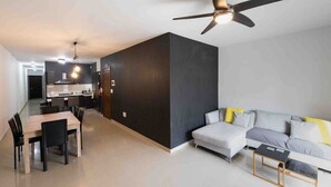 Ein modernes Wohnzimmer mit einer Couch, einem Esstisch mit Stühlen und einem Deckenventilator.