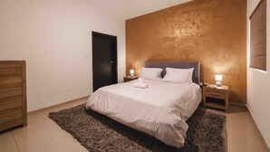 Ein Schlafzimmer mit einem Bett, Nachttischen, einem Deckenventilator und einer Tür.