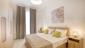 A bedroom with a bed, bedside tables, a lamp, curtains, and a wall art piece.