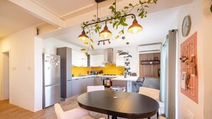 A modern kitchen with a central island, white cabinetry, and a yellow backsplash.
