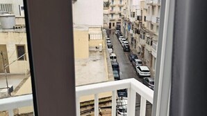 Una calle estrecha con coches aparcados y edificios de varios pisos.
