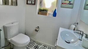 A bathroom with a toilet, sink, and a window. There are framed pictures on the wall and a motivational quote. - Cottonera Cara: Cozy Room with Terrace in the Heart of Bormla (Bormla)