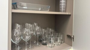 A storage cabinet with shelves holding various glassware and containers. - Cottonera Cara: Cozy Room with Terrace in the Heart of Bormla (Bormla)