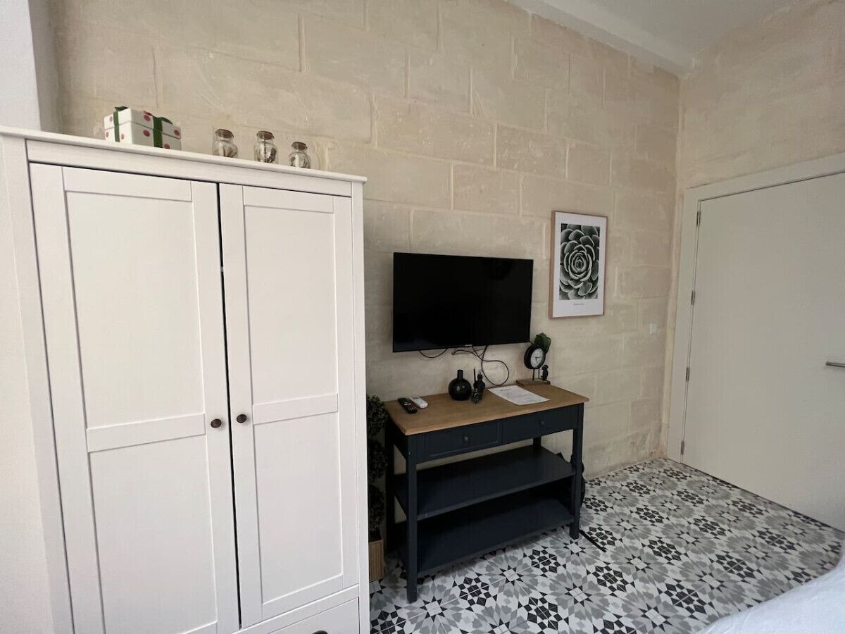 Een badkamer met een witte kast, een houten wastafelmeubel en vloertegels met een patroon.