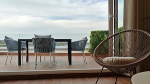 Ein Balkon mit Tisch und Stühlen, ein Korbstuhl und Meerblick.