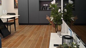 Eine moderne Küche mit grauen Schränken, ein Essbereich mit weißem Tisch und Stühlen und ein Holzboden.