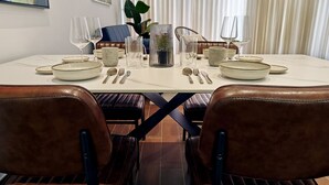 A dining table set with plates, cutlery, and glasses, surrounded by leather chairs.
