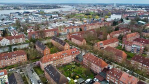 An aerial view of a residential area with multiple apartment buildings, roads, and a river in the background. - Coastal berth I (Rostock)