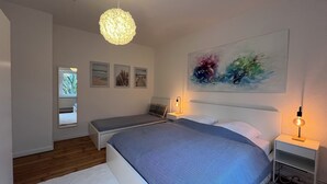 A bedroom with a bed, bedside tables, a hanging light fixture, and artwork on the wall. - Coastal berth I (Rostock)