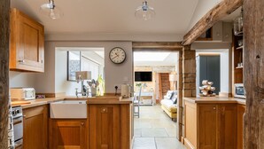 A kitchen with wooden cabinets, a built-in dishwasher, and a stone backsplash. - A beautiful quintessential Cotswold Cottage - Honeysuckle Cottage, Stanton (Stanton)