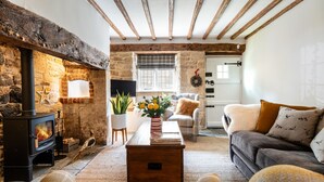 A cozy living room with a stone fireplace, wooden beams, a sofa, and a coffee table. - A beautiful quintessential Cotswold Cottage - Honeysuckle Cottage, Stanton (Stanton)