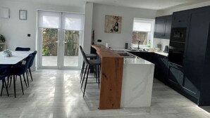 Uma cozinha moderna com armários escuros, uma ilha de madeira e uma área de refeições com mesa e cadeiras.