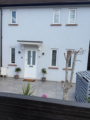 A two-story building with a white exterior, a front door, and two potted plants.