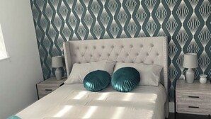Cama bem arrumada com cabeceira estofada, duas almofadas azul-turquesa e um espalha-cama branco.
