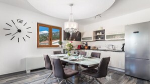 Une cuisine moderne avec un coin repas, une horloge et une vue sur les montagnes.