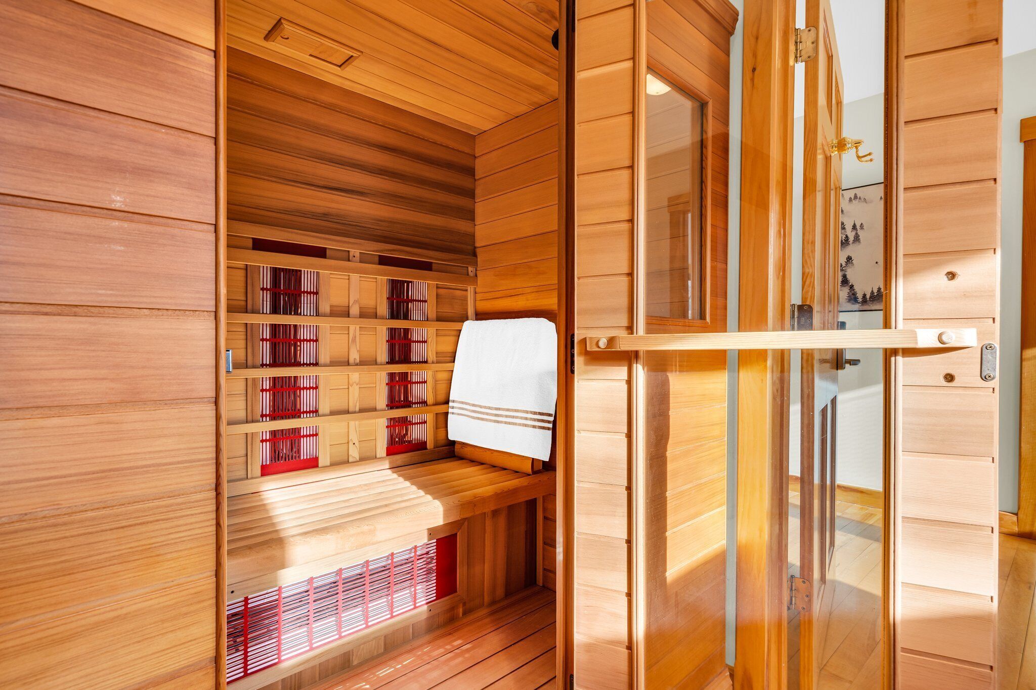 Una sauna con paredes y estantes de madera, un banco y una puerta corrediza.