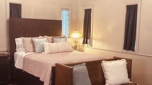 Ein Schlafzimmer mit einem großen Bett, einer Nachttischlampe und Blick ins Freie durch ein Fenster.