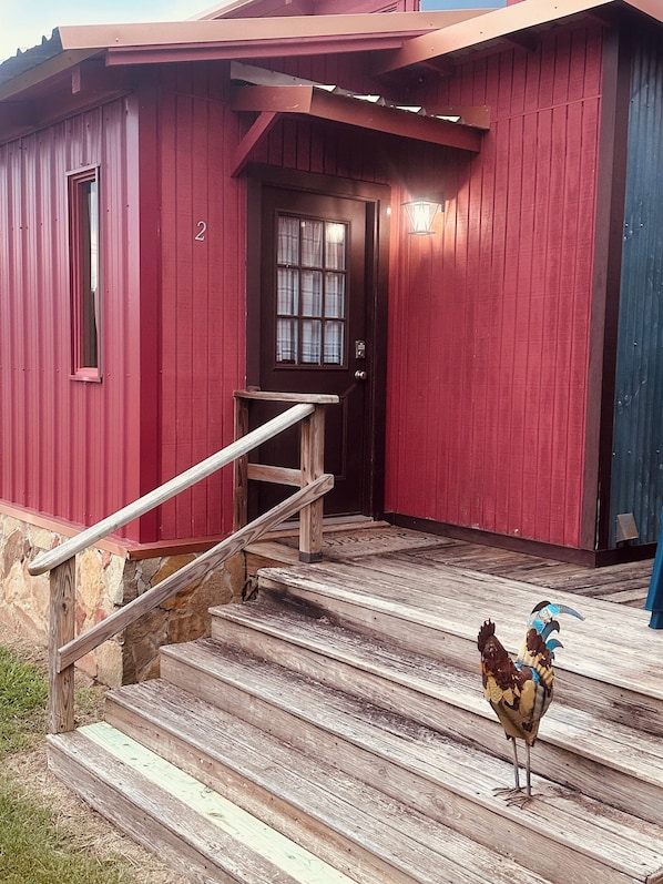 A red building with a wooden staircase leading to a door.