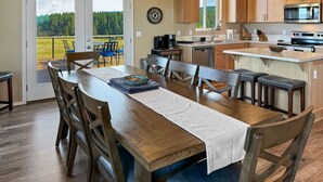 Une cuisine spacieuse dotée de meubles en bois, d’un îlot central et d’un coin repas avec une grande table et des chaises.