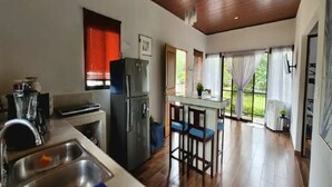 A kitchen with a refrigerator, sink, and bar stools. - Villa Marina (Nosara)
