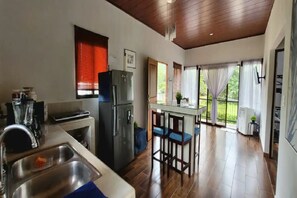 A kitchen with a refrigerator, sink, and bar stools. - Villa Marina (Nosara)