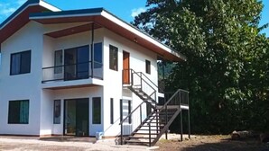 A two-story house with a balcony, a staircase, and a front door. - Villa Marina (Nosara)