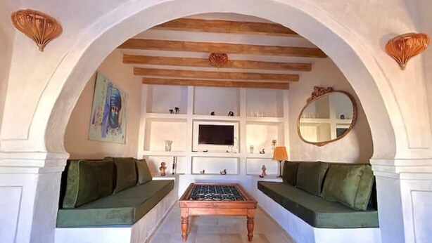 A living room with a fireplace, green sofas, a TV, and decorative items. - Golden Sand House 2 (Hammamet)