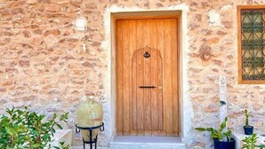 A stone wall with a wooden door, a small step leading to the door, and potted plants on either side. - Golden Sand House 2 (Hammamet)
