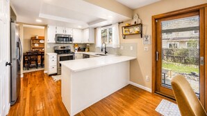 Une cuisine moderne avec des meubles blancs, un îlot central et un coin repas comprenant une table et des chaises en bois.