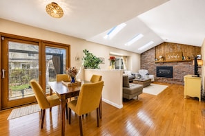Una sala de estar moderna con comedor, chimenea y vistas al exterior.