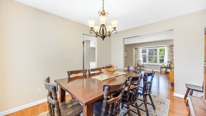 Un coin repas avec une table en bois, des chaises, un lustre et un tapis.