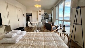 A hotel room with a bed, a desk, a chair, a small table, and a view of the sea. - Studio with great view of the Beagle Channel (Ushuaia)
