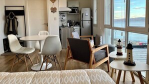 A compact living space with a dining area, kitchen, and large windows offering a view of the sea. - Studio with great view of the Beagle Channel (Ushuaia)