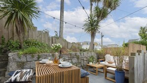 An outdoor patio with wooden furniture, stone walls, and a wooden fence. - Offshore -  Carbis Bay (Carbis Bay)