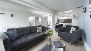 A modern living room with two grey sofas, a coffee table, and a vase with flowers. - Offshore -  Carbis Bay (Carbis Bay)