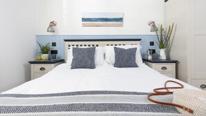 A neatly made bed with white and gray bedding, a blue and white wall, and a small painting of a beach. - Offshore -  Carbis Bay (Carbis Bay)