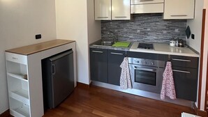 A compact kitchen with white cabinets, a built-in dishwasher, a stove, and a sink.