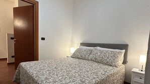 A bedroom with a bed, a nightstand, a door, and a ceiling fan.