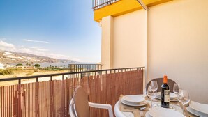 Ein Balkon mit Esstisch, der einen malerischen Blick auf eine Küstenlandschaft bietet.