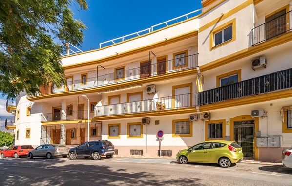 Un hotel a più piani con balconi, un'area di parcheggio e un cielo azzurro intenso.