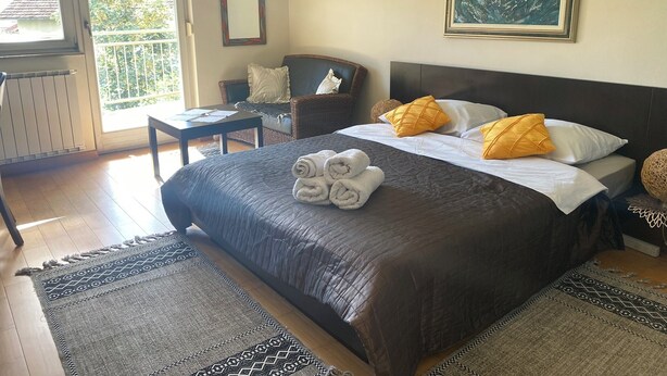 Un dormitorio con una cama grande, una silla, una mesa y un cuadro en la pared.