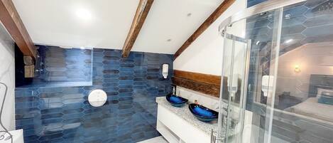 Een moderne badkamer met een glazen douchecabine, een wit toilet en een wastafel met twee blauwe kommen.