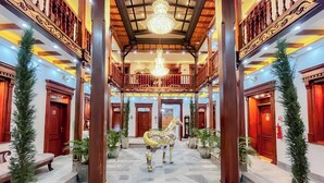 A grand lobby with a central staircase, ornate wooden railings, and a chandelier. - Hotel & Rooftop King Experience by David (Quito)