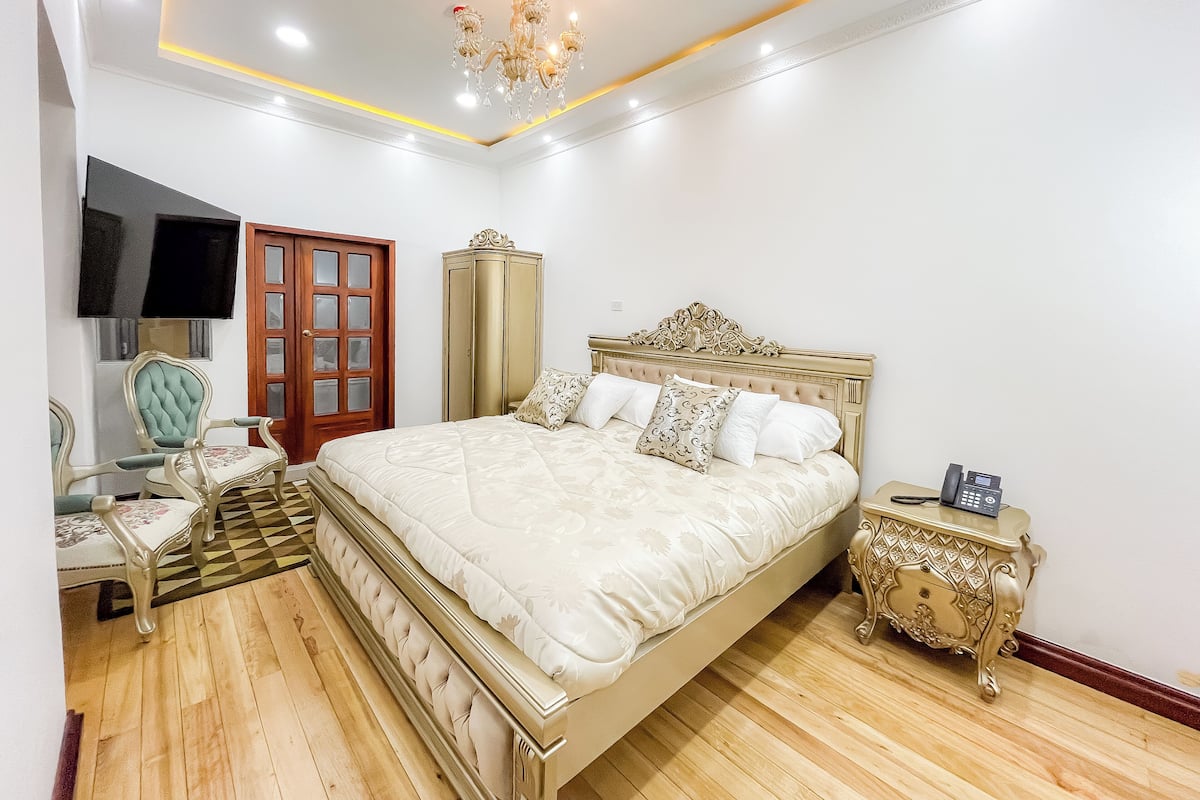 A bedroom with a large bed, a wardrobe, a television, and a telephone.