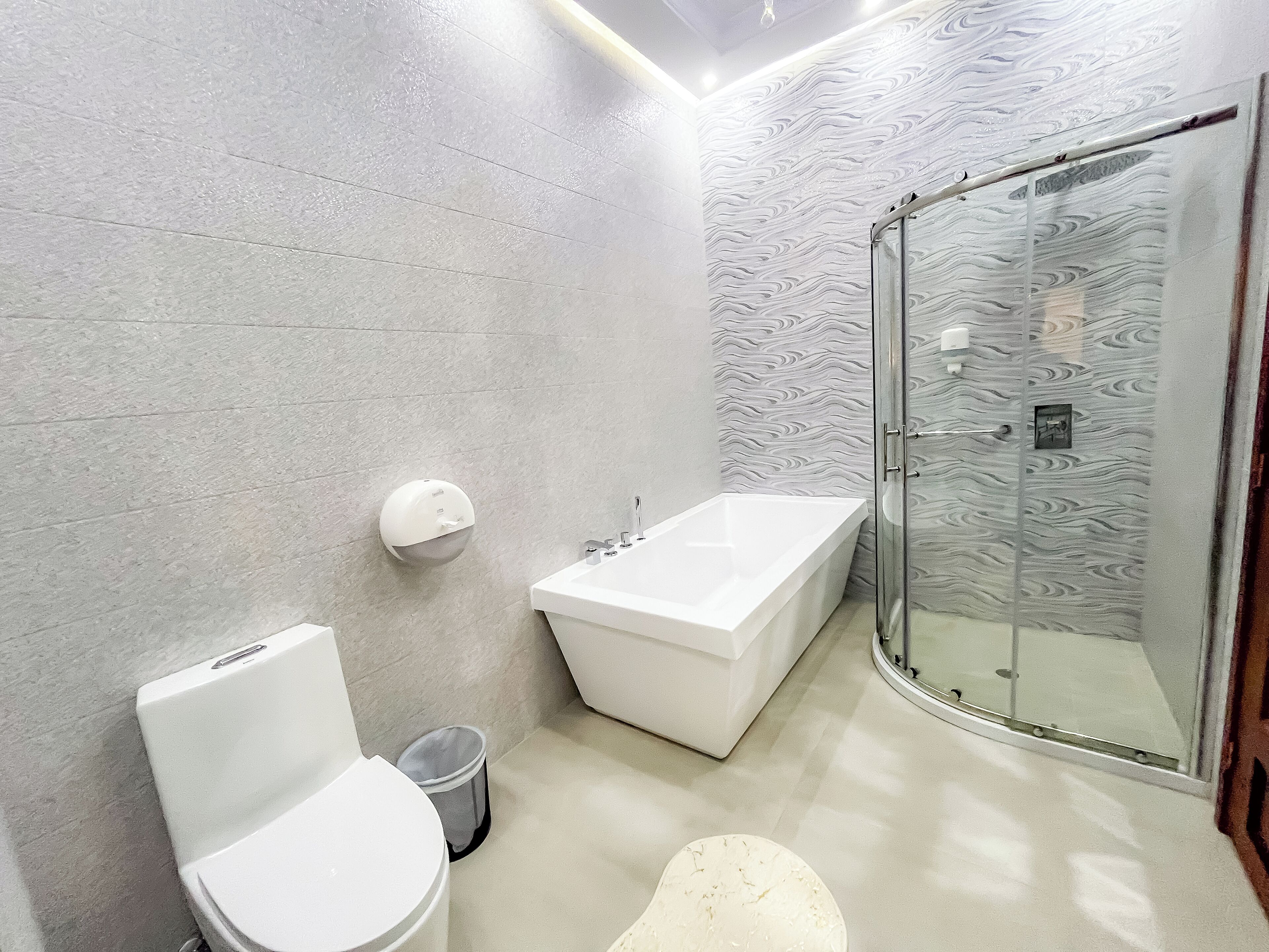 Ein modernes Badezimmer mit Toilette, Badewanne und einer Duschkabine aus Glas.
