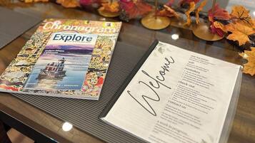 A table with a magazine, a welcome card, and candles.