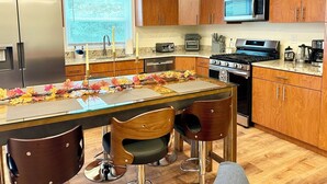 Une cuisine moderne avec des meubles en bois, des appareils électroménagers en acier inoxydable et un îlot central doté de chaises.